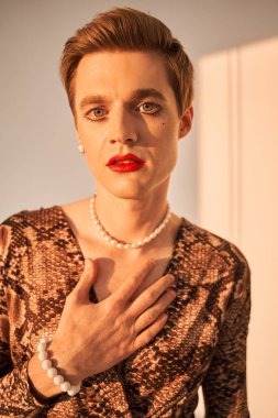 Feminen gömlekli, makyajlı, poz veren bir gay.