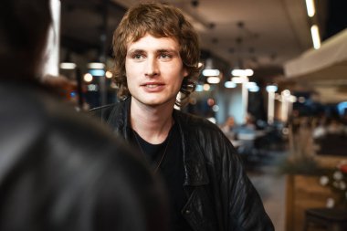 Deri ceketli hayalperest bir adam kadınına bakıyor ve gülümsüyor.