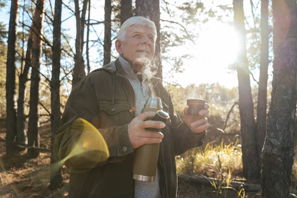 Man looking at the distance and drinking hot tea while relaxing after walking — Stock Photo, Image