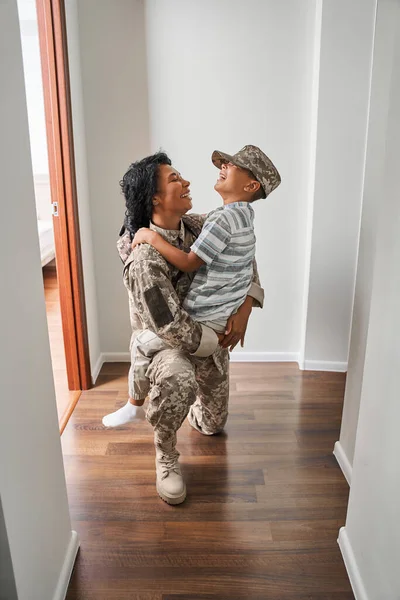 Negro soldado femenino sostiene hijo de armas en casa — Foto de Stock