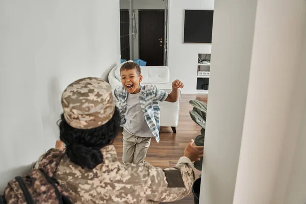 Щасливий чорний хлопчик зустрічає матір вдома після армії — стокове фото