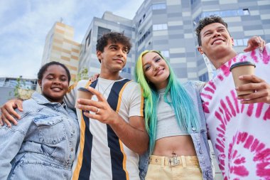 Kızlar ve erkekler ellerinde kahveyle kentte