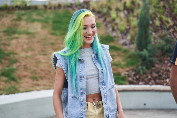 Chica joven con el pelo de color riendo en voz alta mientras camina por la calle — Foto de Stock