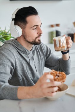 Kulaklık takan çekici iş adamı laptopta neşeyle çalışıyor.