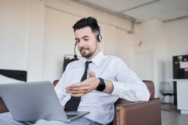 Çağrı merkezi operatörü koltukta oturup müşterilerle sohbet ediyor.