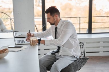Masada oturan yetenekli bir girişimci ve evde çalışırken bilgisayarını kullanıyor.