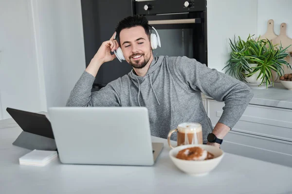 Kulaklık takan bir adam çalışırken dizüstü bilgisayara bakıp gülümsedi.