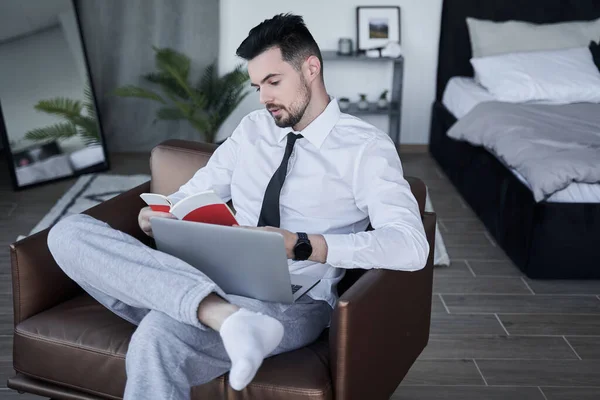 Empresario sentado en el sillón en la postura relajada y leyendo algunas notas — Foto de Stock