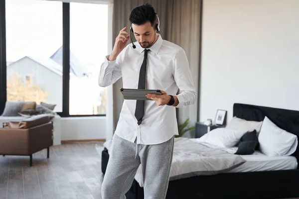 Hombre con auriculares mirando a la tableta mientras trabaja con los clientes desde casa — Foto de Stock