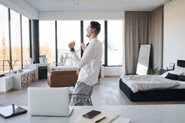 Чоловік в офіційній сорочці радіє чомусь, стоячи вдома після роботи — стокове фото