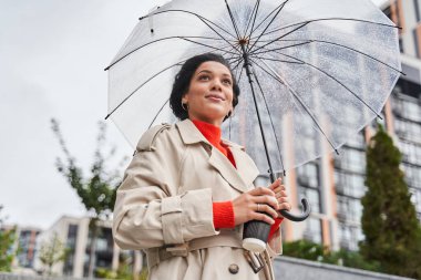 Şemsiye tutan neşeli kız yağmur damlaları damlatıyor ve gülümsüyor.