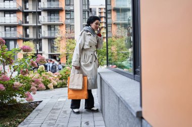 Kadın, vitrinin önünde duruyor ve ilgiyle içine bakıyor.