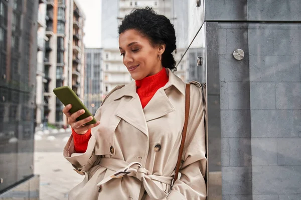 Mulher multirracial usando smartphone na rua enquanto verifica e-mails ou mensagens — Fotografia de Stock