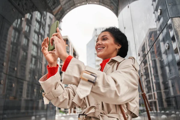 Frau in warmer Kleidung hält Videoanruf mit Freunden und lächelt zahm in die Kamera — Stockfoto