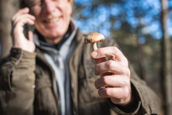 Senior homme tenant champignon et bavarder via smartphone avec plaisir sourire — Photo