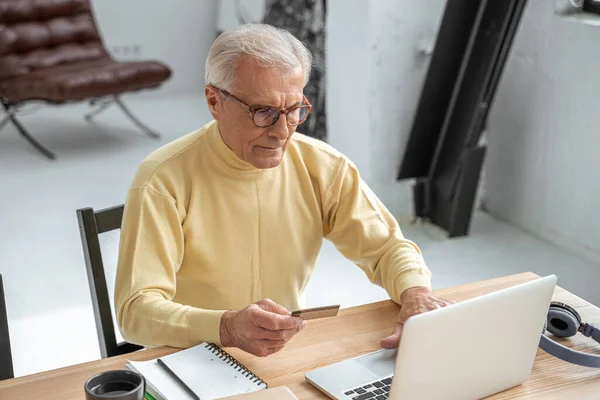 Homme utilisant la carte de crédit pour faire du shopping en ligne tout en étant assis devant l'ordinateur portable — Photo