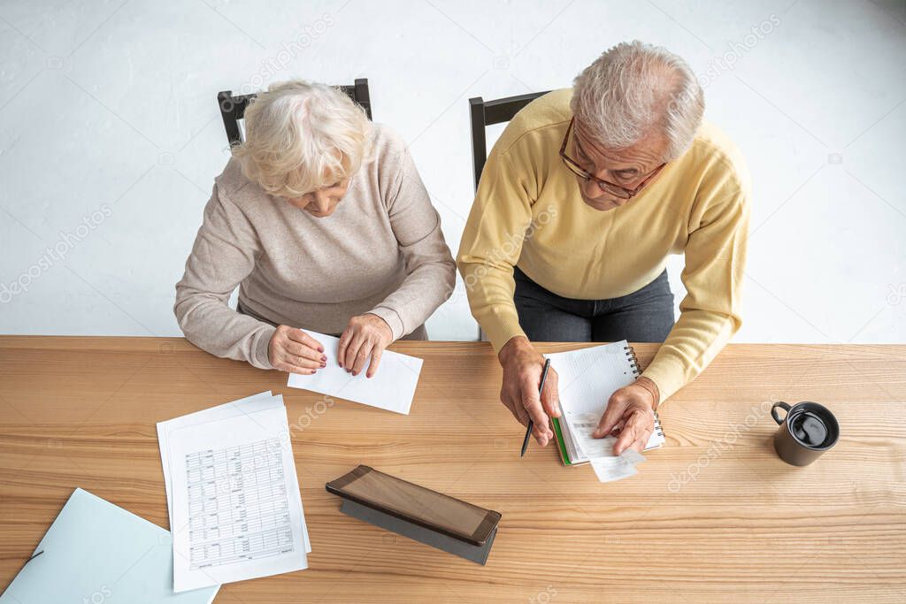 Retirement couple checking accountancy and bills while looking at each other