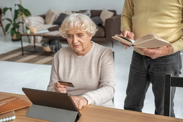 Mujer usando tarjeta de crédito para ir de compras en línea mientras está sentado frente a la tableta — Foto de Stock