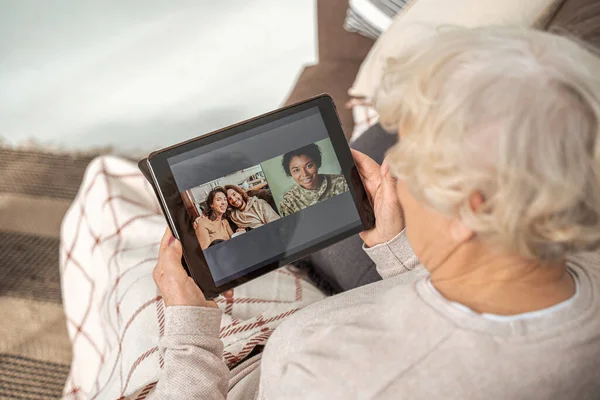Жінка насолоджується відео розмовою через планшет зі своїми родичами сидячи — стокове фото