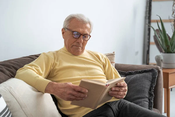 Härlig gammal man som kopplar av på soffan med kuddar hemma — Stockfoto