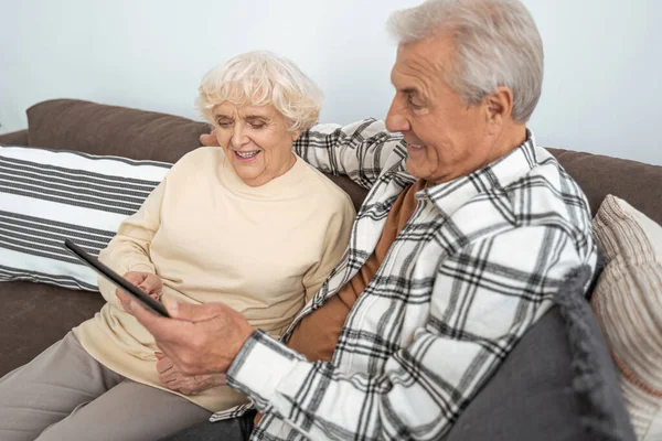 Glückliches Senioren-Paar plaudert im Wohnzimmer mit Tablet-Computer — Stockfoto