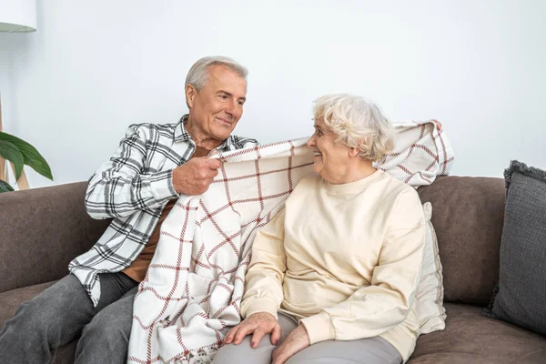Neşeli olgun erkek ve kadın evde kanepede oturan — Stok fotoğraf