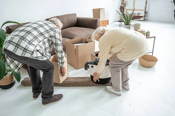 Старша пара розпаковує коробки своїх речей під час переїзду в новий будинок — стокове фото