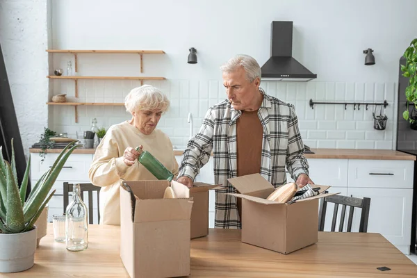 Volwassen paar staan in de keuken met verhuisdozen bij nieuw huis, terwijl het uitpakken van dingen — Stockfoto