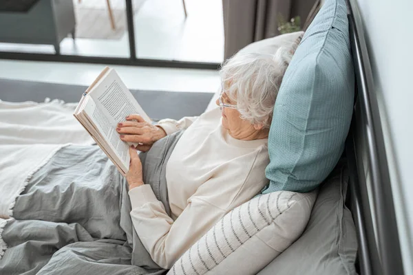 Mujer linda jubilación está leyendo en el dormitorio —  Fotos de Stock