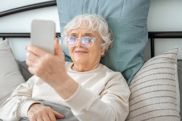 Весела літня жінка робить селфі на своєму мобільному телефоні — стокове фото