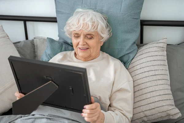 Mujer mayor recordando momentos mientras yacía en la cama —  Fotos de Stock