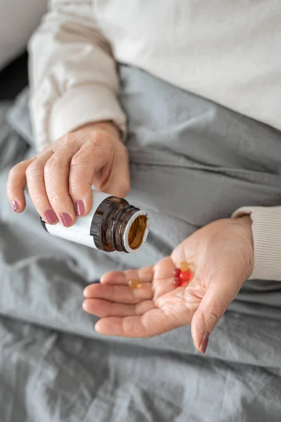Doente mulher idosa deitada na cama com pílulas — Fotografia de Stock