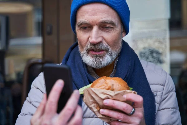 Homme mûr ayant appelé avec quelqu'un au smartphone alors qu'il était assis à la table — Photo