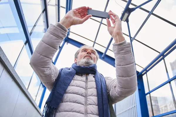 Homme âgé tenant smartphone et faisant la photo de la gare — Photo