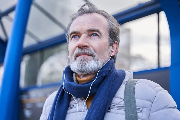 Portrait d'un bel homme âgé regardant ailleurs et souriant tout en écoutant de la musique — Photo