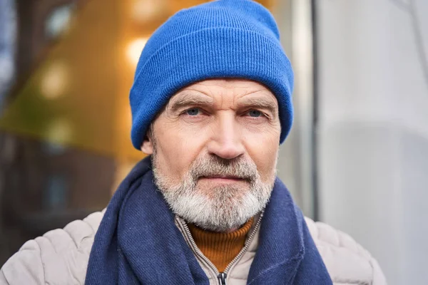 Grey haired male wearing blue hat looking at the camera while sitting — Φωτογραφία Αρχείου