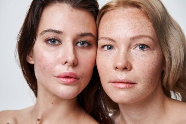 Çıplak omuzlu beyaz kadınlar ve ayakta duran farklı ten tipleri.