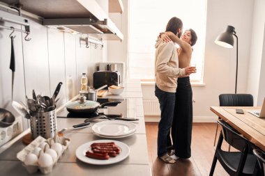 Kız arkadaşı elinde meyve suyu bardağıyla erkek arkadaşını kucaklıyor.