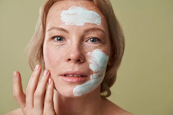 Spa chica con expresión facial complacido y máscara de arcilla en la cara conseguir tratamientos de belleza — Foto de Stock