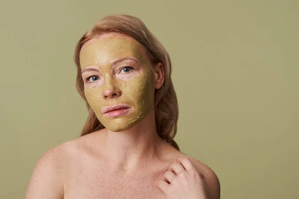 Szeplős szépség fiatal nő használ egy zöld agyag arc maszk, miközben a kamerába — Stock Fotó