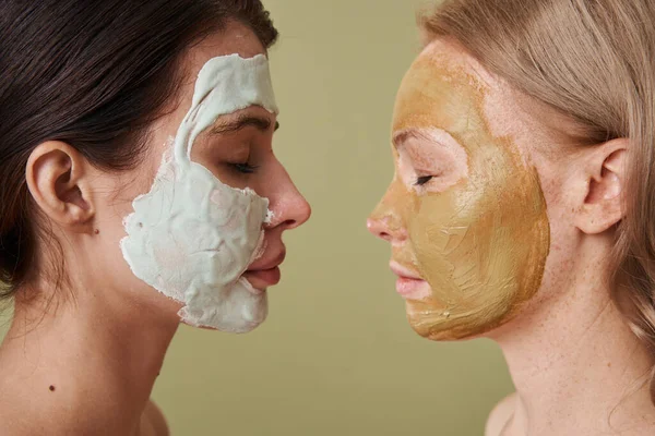 Wanita dengan masker kulit alami berdiri berhadapan satu sama lain dengan mata tertutup — Stok Foto