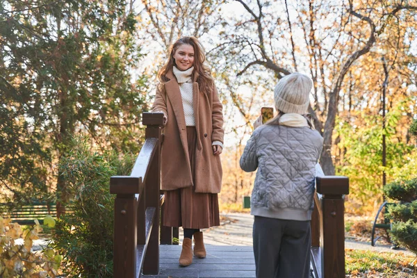 Девочка-подросток делает фотосессию для своей прекрасной матери, стоя в парке — стоковое фото