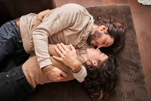 Amante casal deitado no sofá dentro de casa e abraçando — Fotografia de Stock