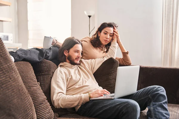 Mujer acostada en el sofá y mirando a la pantalla del ordenador portátil — Foto de Stock