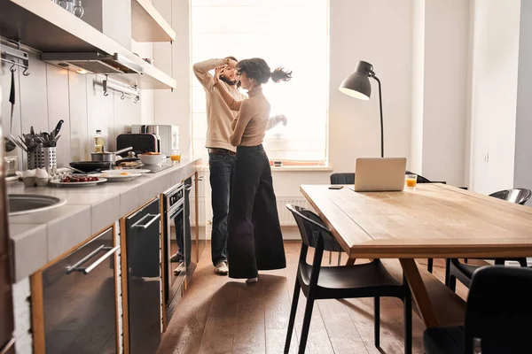 Los cónyuges disfrutando de momento tierno en la cocina en casa juntos —  Fotos de Stock