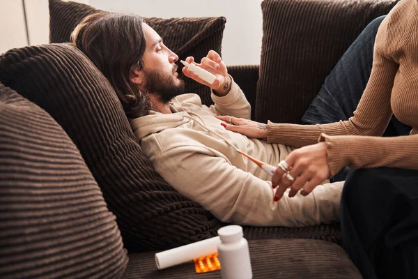 Homem deitado no sofá e usando spray para o nariz — Fotografia de Stock