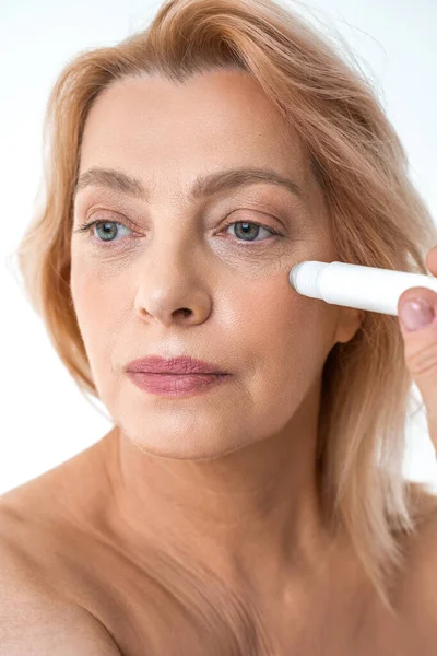 Mulher aposentadoria loira usando o instrumento de massagem facial de rolo enquanto olha para longe — Fotografia de Stock