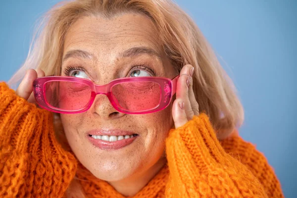 Lebhafte sommersprossige Frau mit moderner pinkfarbener Sonnenbrille, die nach oben schaut — Stockfoto