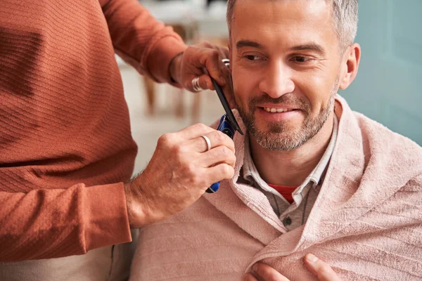 Knappe man die thuis zijn baard laat knippen terwijl zijn voorzichtige vader hem helpt — Stockfoto