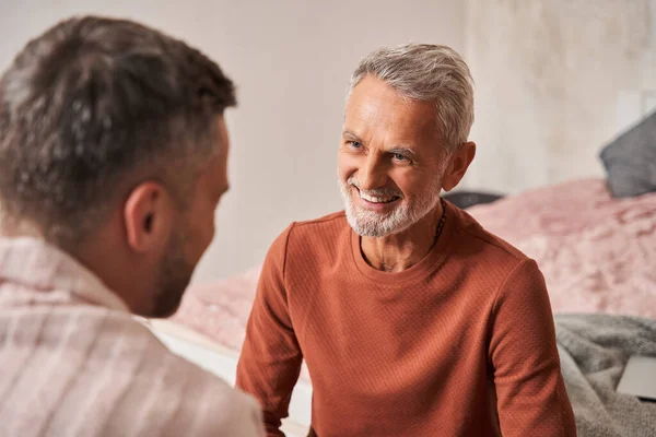 Man herinneren iets grappigs met volwassen zoon terwijl zitten met elkaar thuis en lachen — Stockfoto